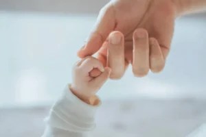 Bebé cogiendo la mano de su madre.